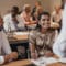 Group of business people sit at desks and face speaker in small conference room