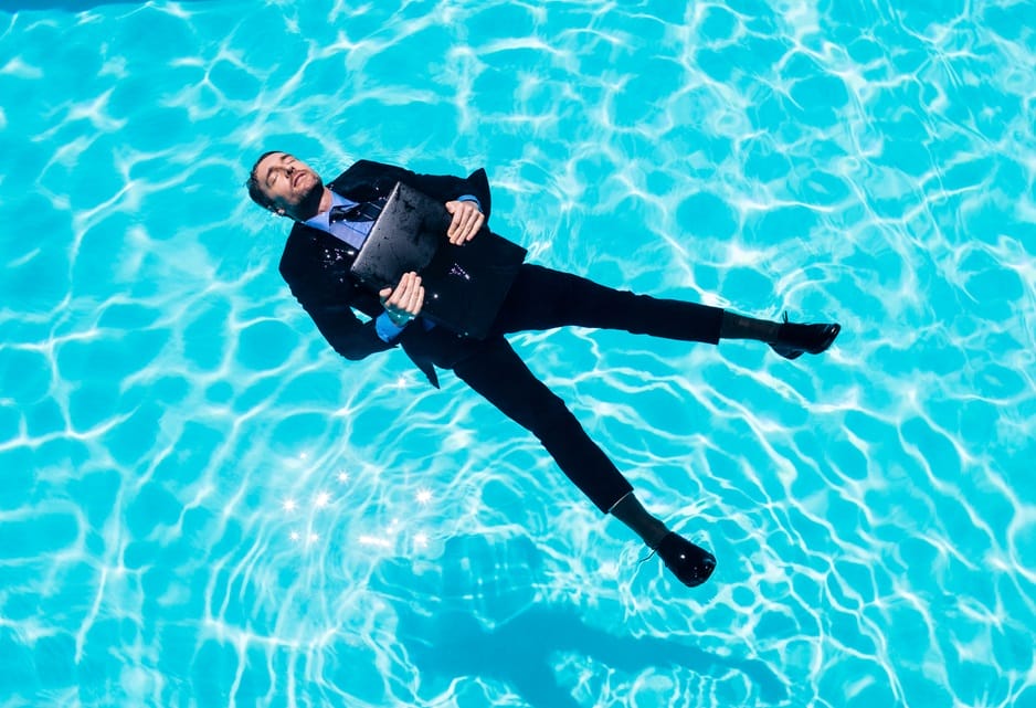 Man in Suit Floats in Pool Peacefully