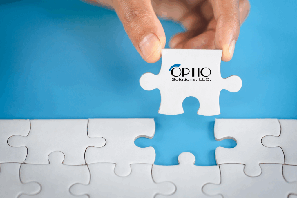 Hand placing last puzzle piece, with Optio Solutions logo, into puzzle.