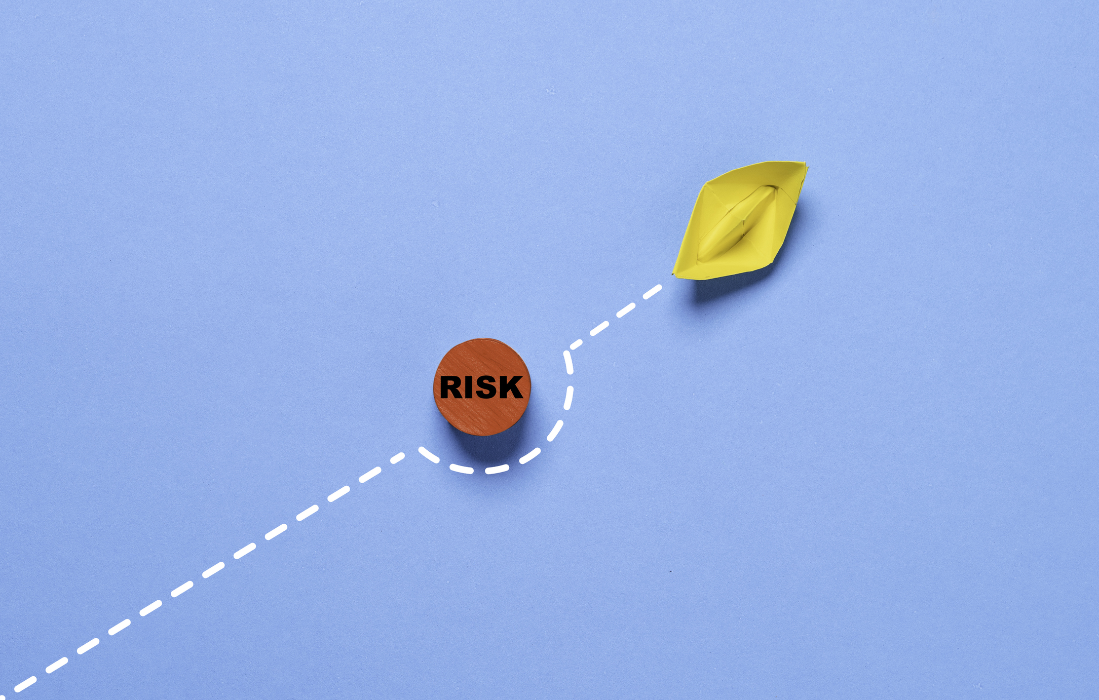 Yellow paper boat sails away from the red risk danger on blue ocean for risk assessment and analysis concept