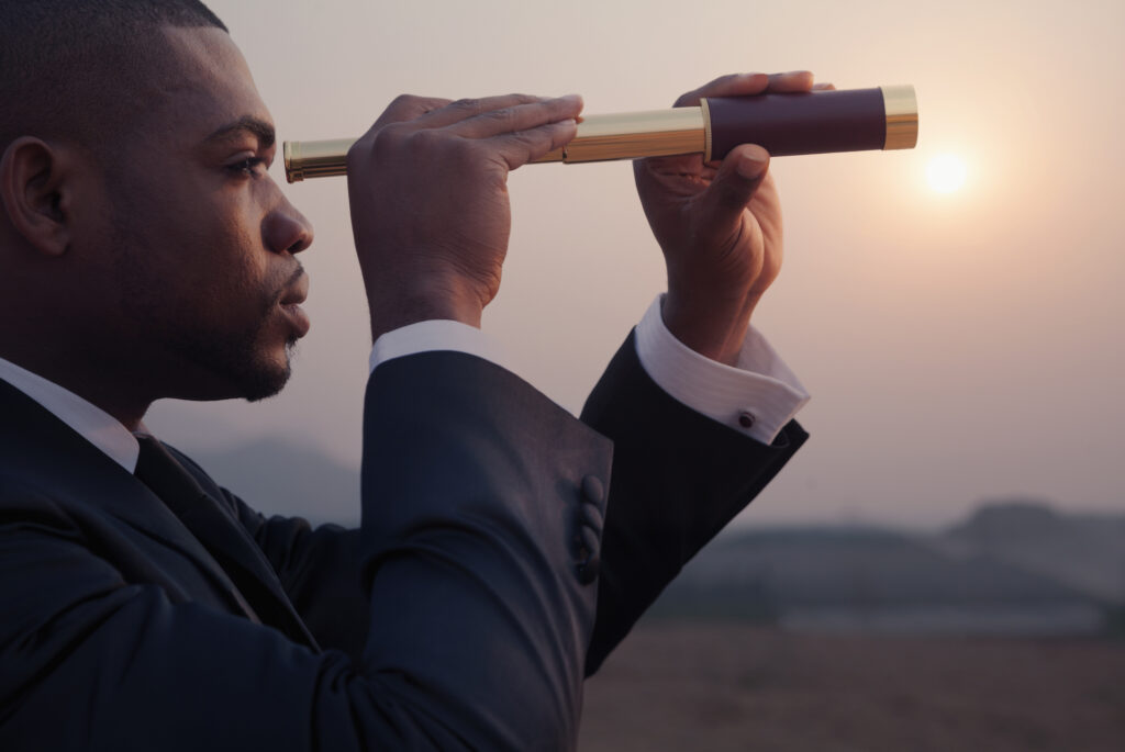 Young businessman looking through telescope in an outdoor landscape.