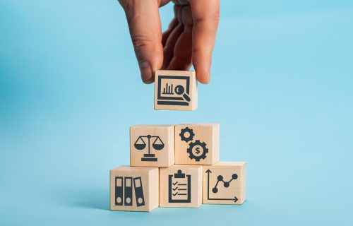 Business concept - Holding wooden cubes with different financial icons on the cubes