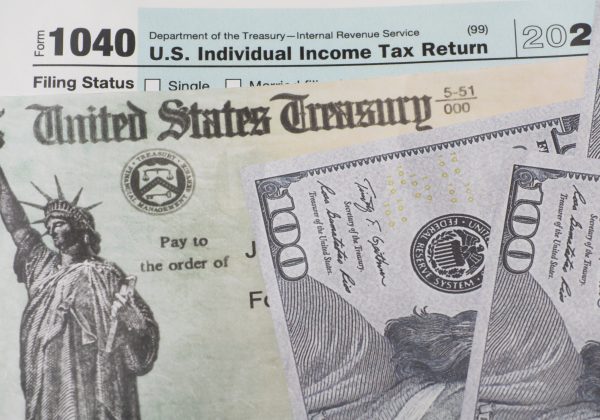Prop US currency and treasury department check and top of 1040 tax form.