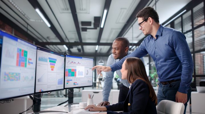 Diverse Group in office looking at financial dashboard screens.