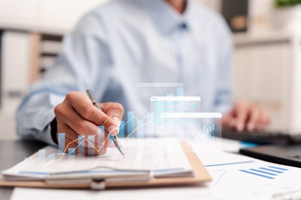 Financial planning and business analytics concept featuring a professional reviewing reports, charts and performance data. Strategic budgeting, investment analysis.